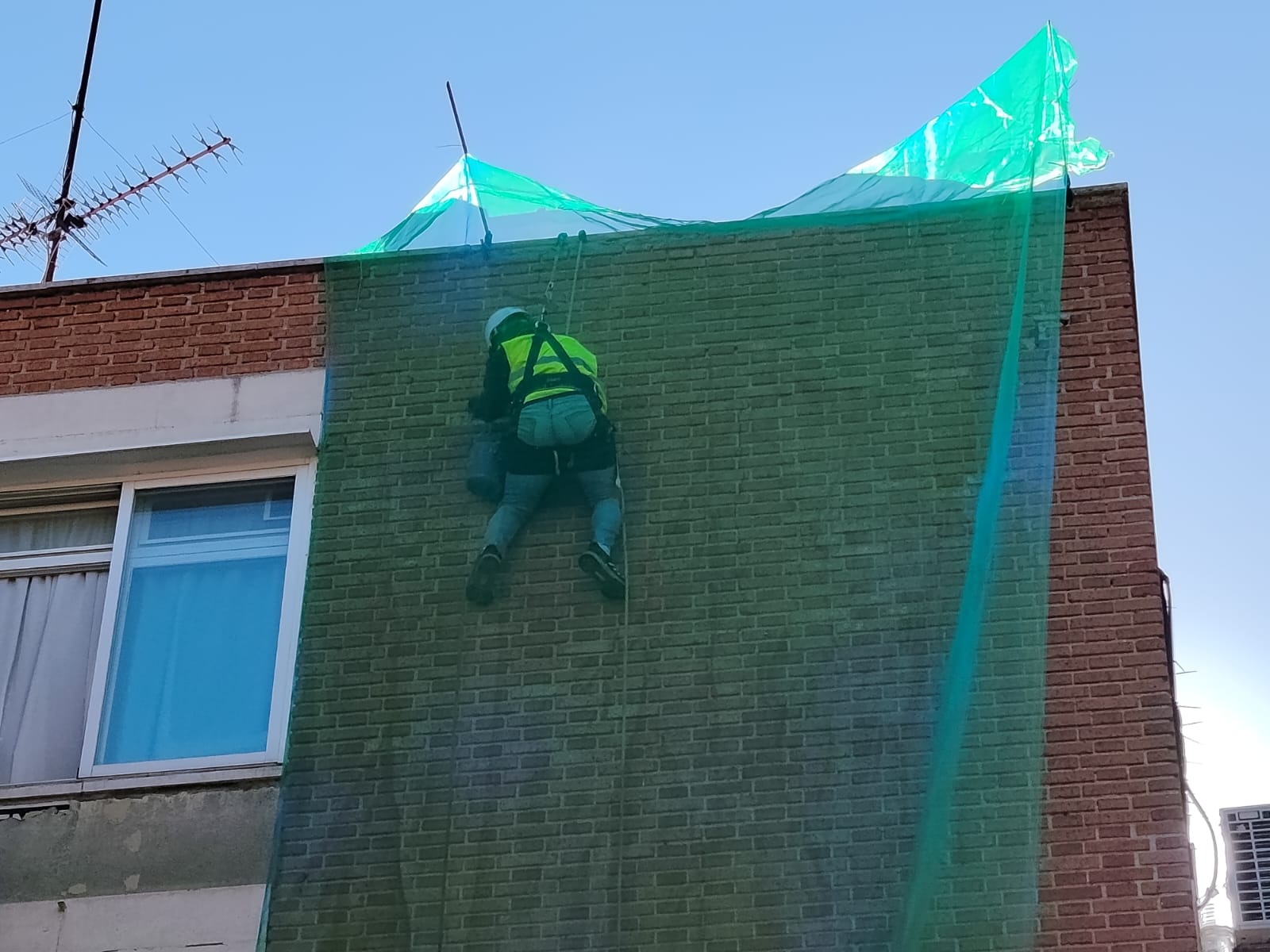 Operario de Anntha Servis rehabilitando fachada con red de protección